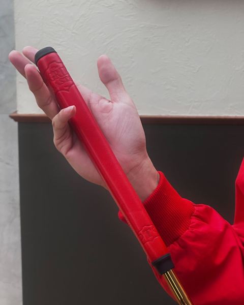 Red leather grip and gold shaft in hand